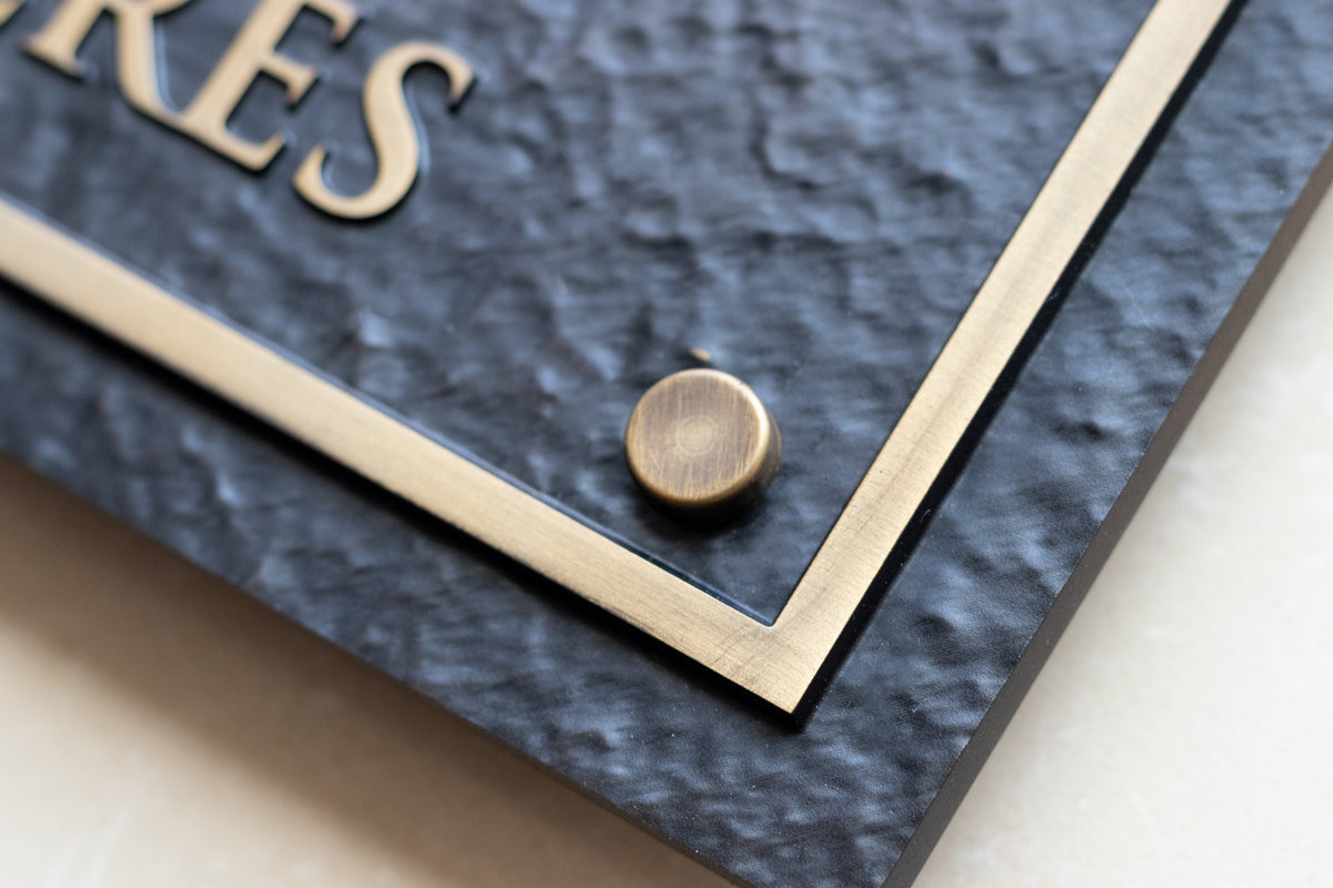 Close-up of brass border, textured finish and decorative mount on arch address plaque
