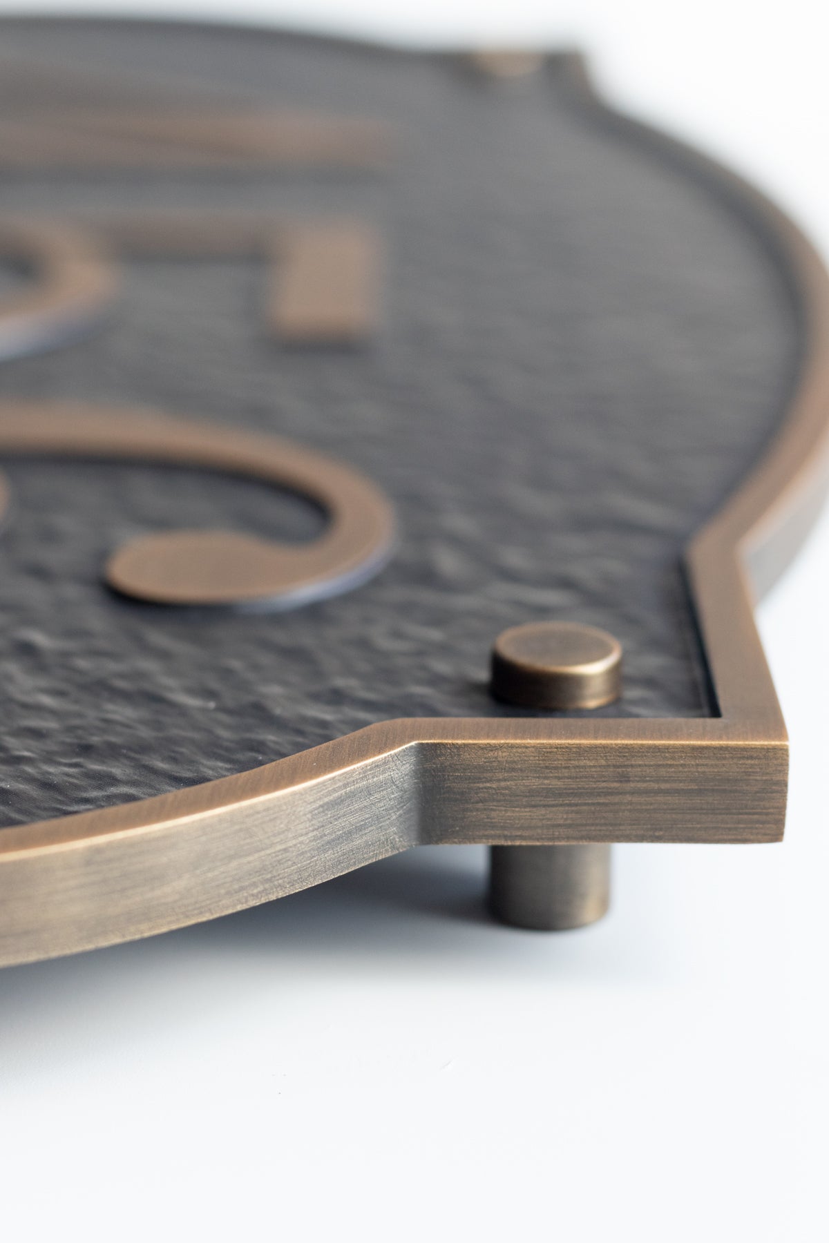 Close-up of the antique brass edge and floating standoff on an aluminum address plaque